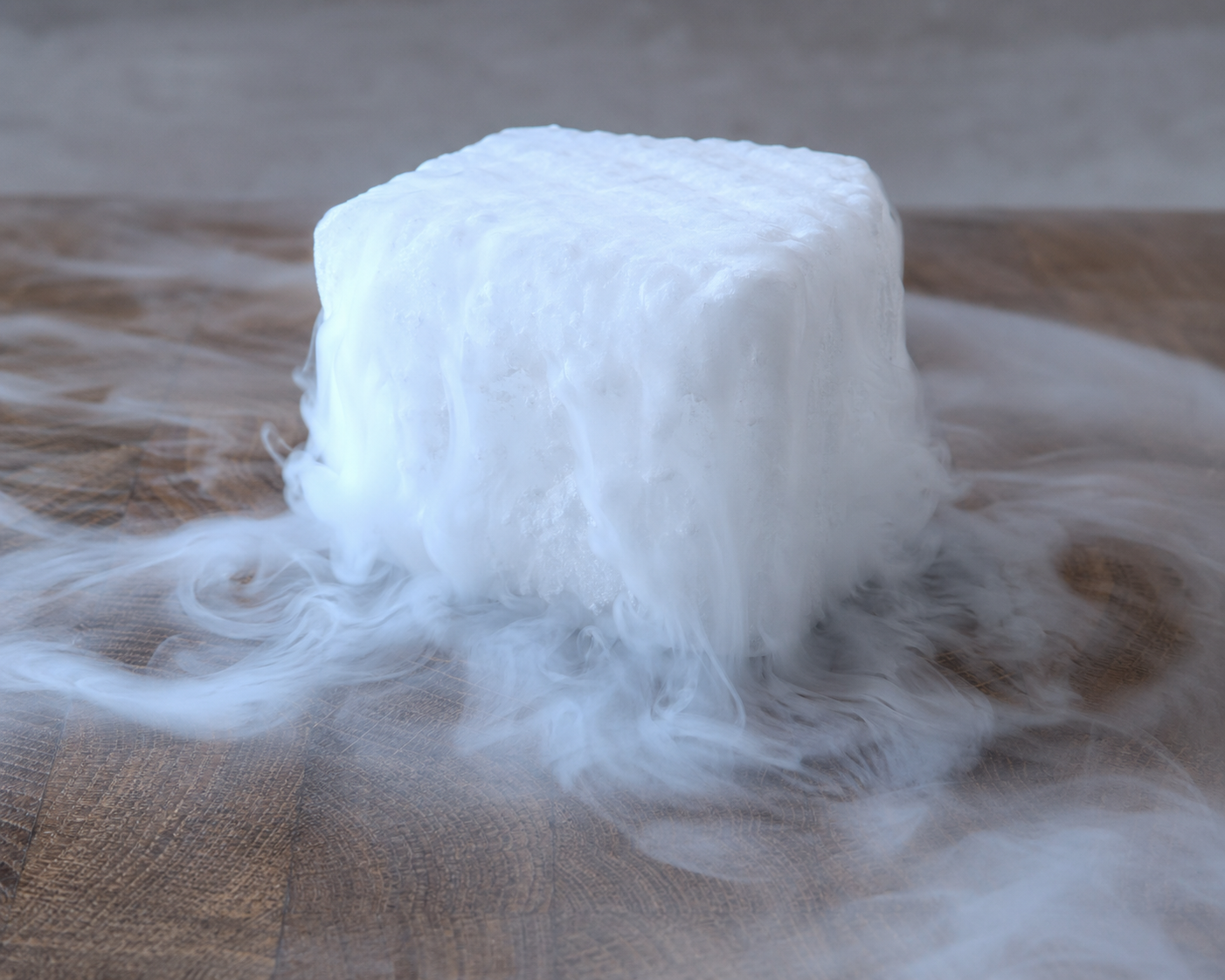 Torris (fast koldioxid) som ryker — vit CO₂-imma flödar nedåt och samlas runt blocket.